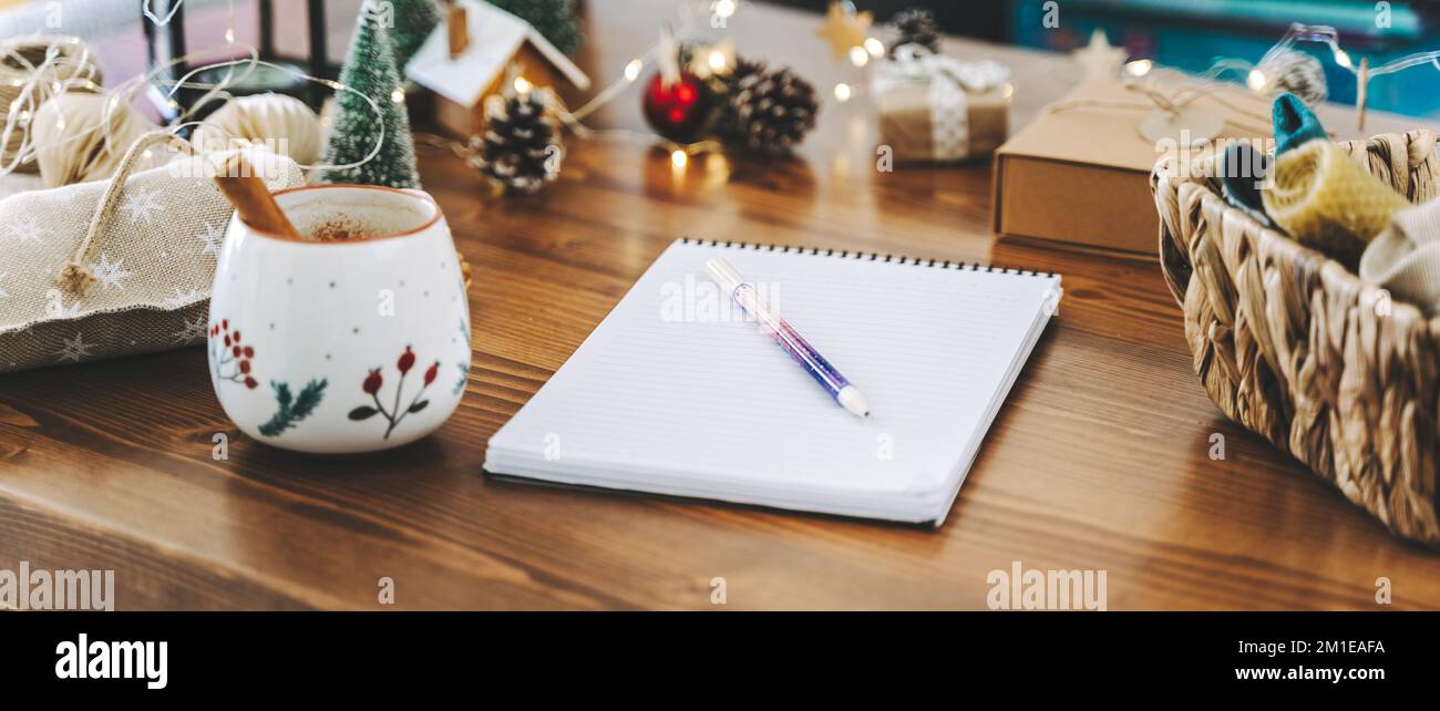 Woman hand holding pen on notepad at home on winter holidays xmas. Goals plans make to do and wish list for new year christmas concept, girl writing Stock Photo
