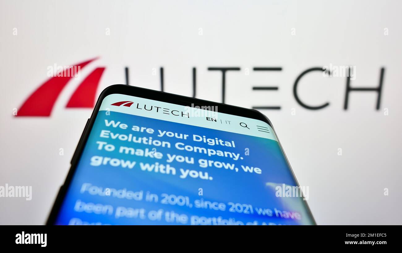 Mobile phone with webpage of information technology company Lutech S.p.A. on screen in front of business logo. Focus on top-left of phone display. Stock Photo