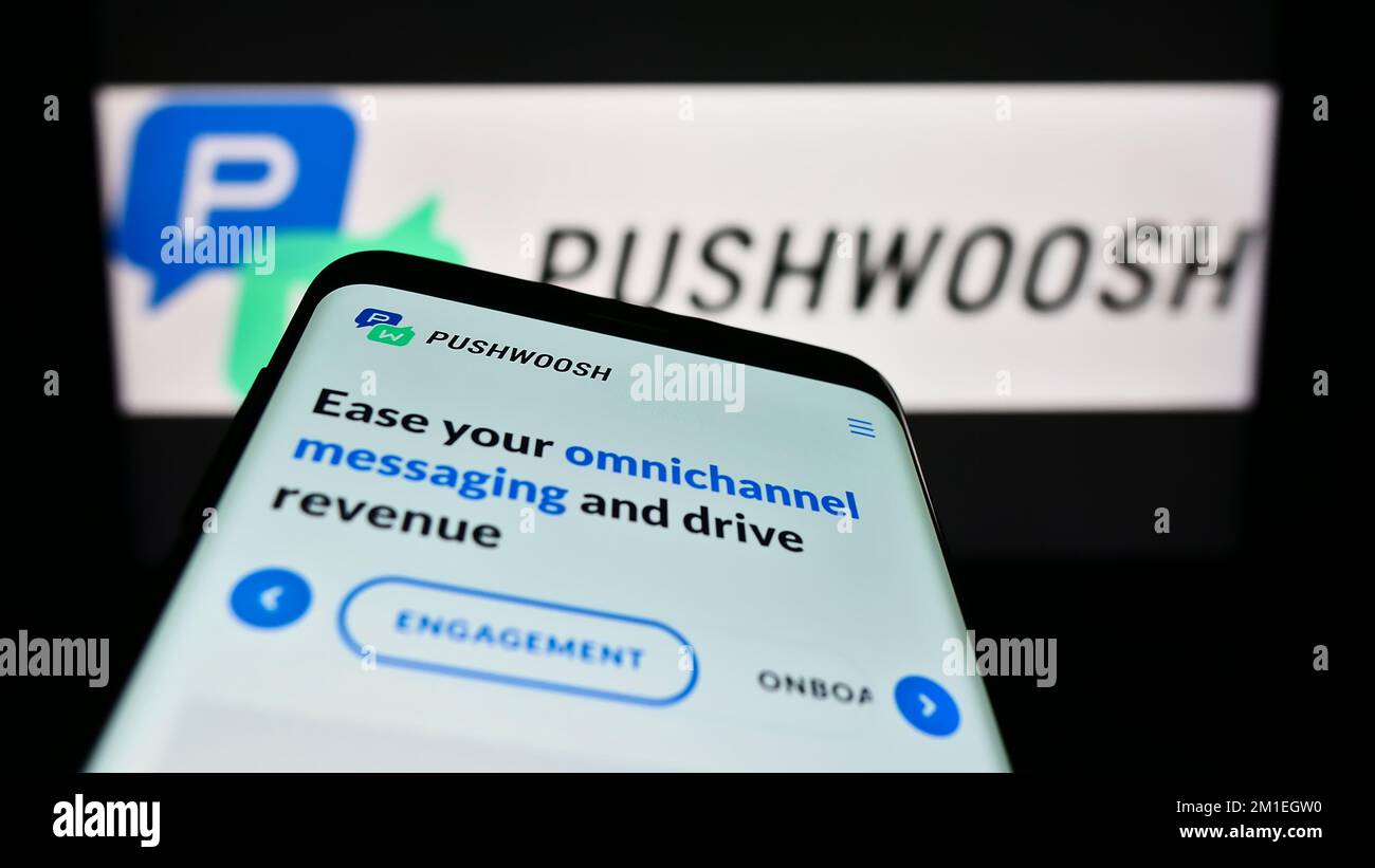 Smartphone with webpage of US marketing platform company Pushwoosh Inc. on screen in front of business logo. Focus on top-left of phone display. Stock Photo