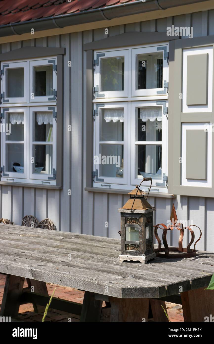 Outdoor wooden table with lantern in front of a wooden house Stock Photo