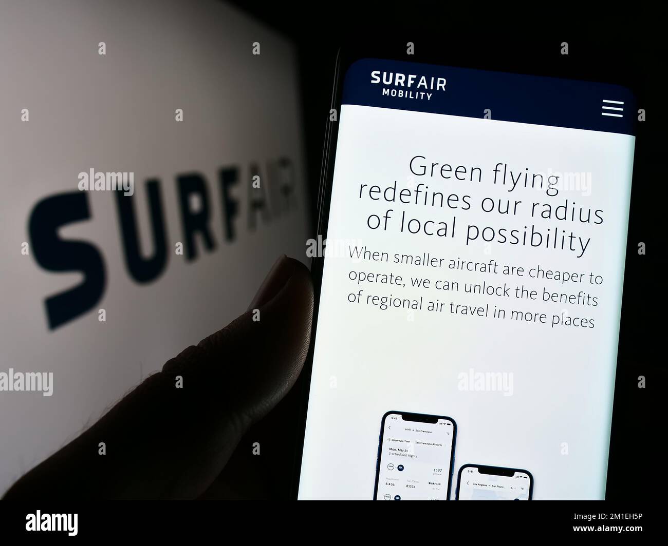 Person holding cellphone with webpage of US aviation company Surf Air Mobility on screen in front of logo. Focus on center of phone display. Stock Photo
