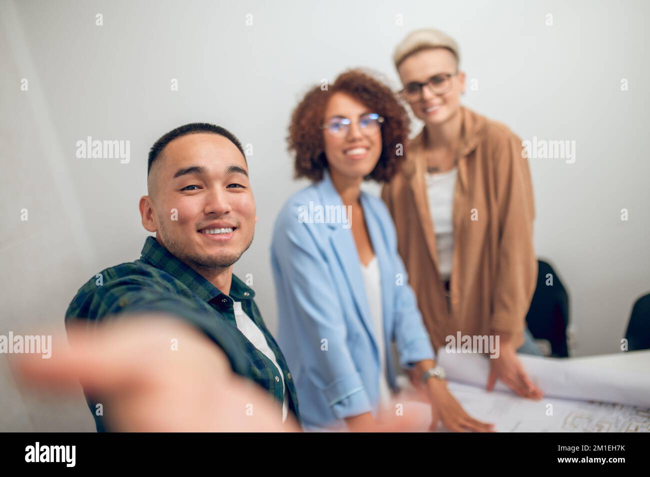 Cheerful draftsman photographing himself and coworkers at the staff meeting Stock Photo