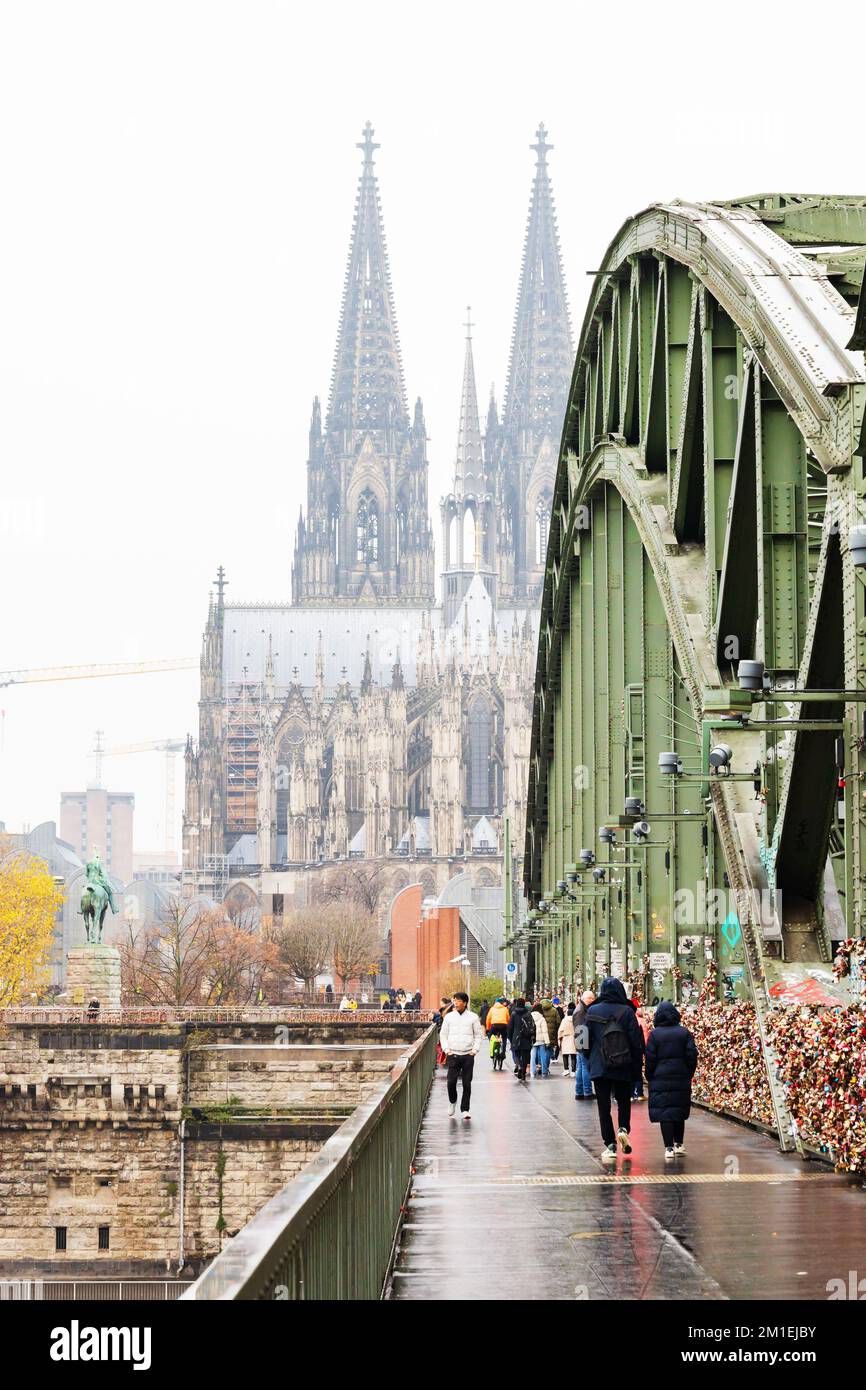 Pedestrians get a foggy View of Koln Cologne cathedral Dom, from the Hohenzollernbrucke, Hohenzollern bridge, Germany. Stock Photo