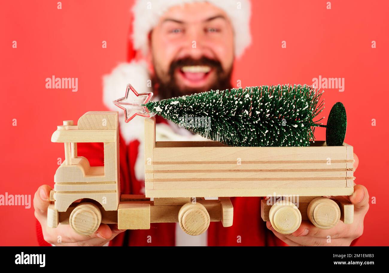 Christmas tree on wooden toy truck car. Santa Claus with firtree
