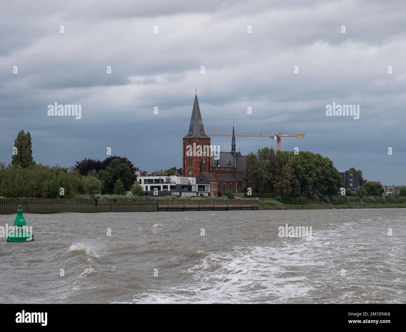 The Sint Martinus Church from the river Scheldt in Zwijndrecht, Belgium on a cloudy day Stock Photo