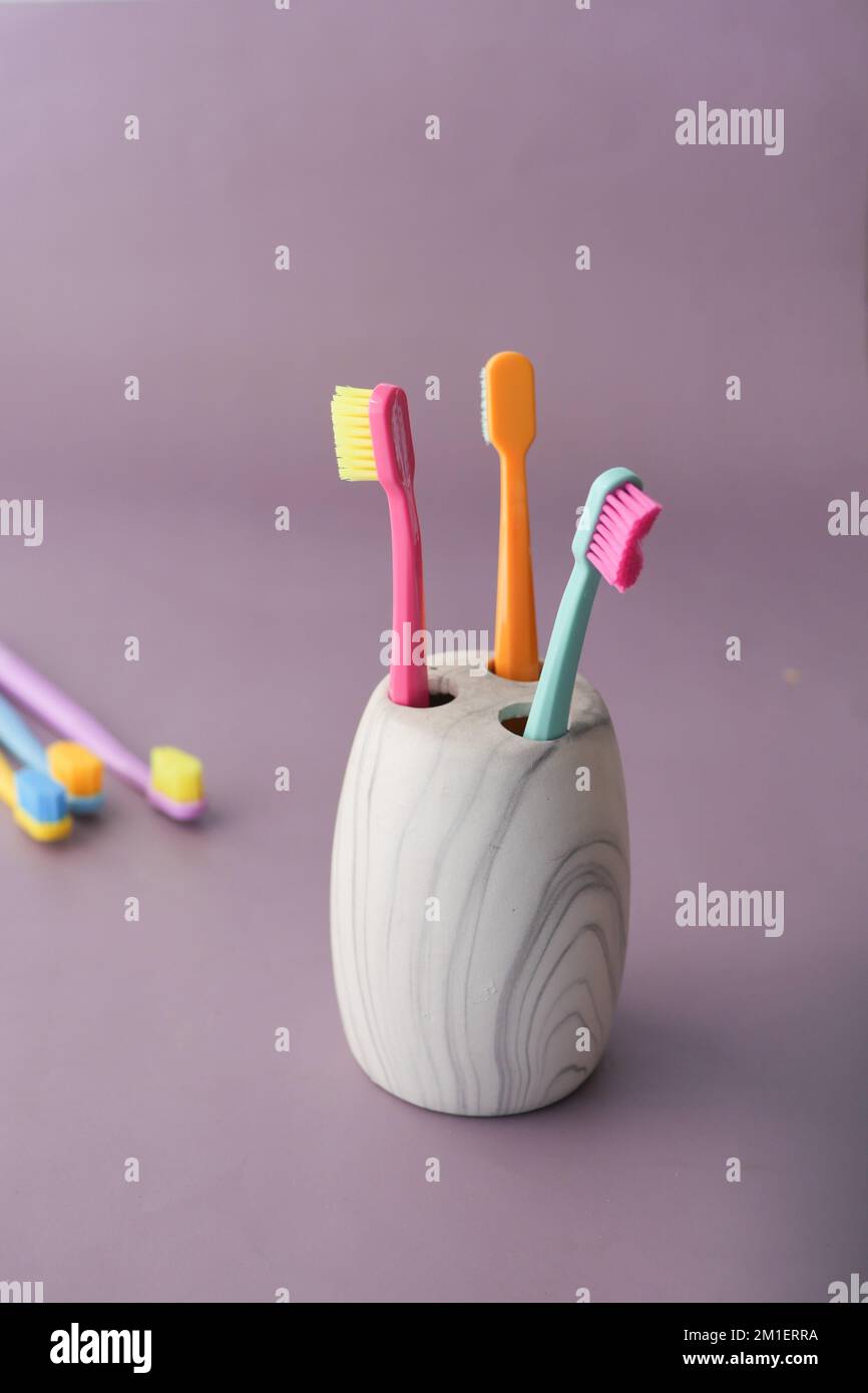 colorful toothbrushes in white mug on purple background Stock Photo - Alamy