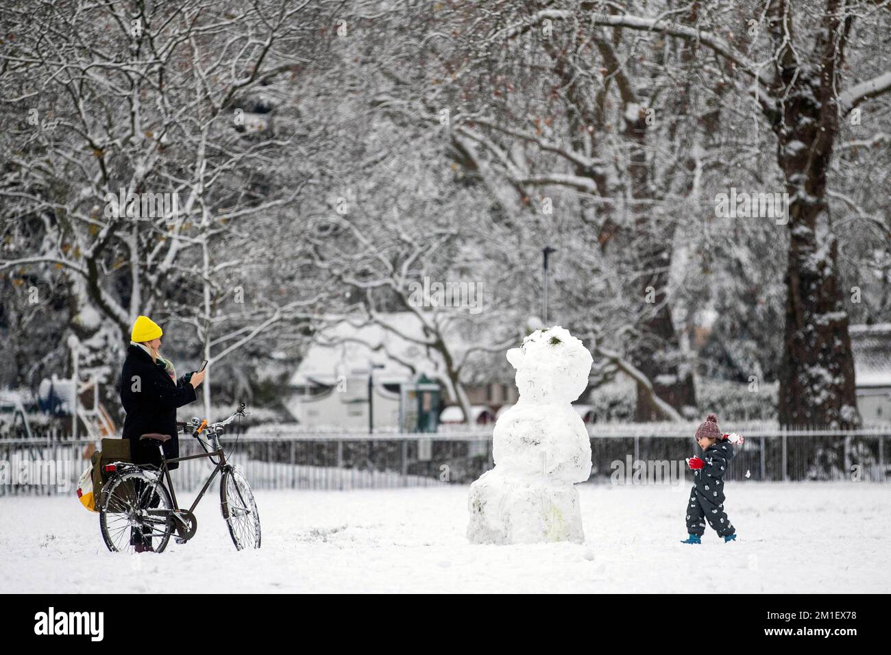 A people beside a snowman in Kennington Park, London. Snow and ice have swept across parts of the UK, with cold wintry conditions set to continue for days. Picture date: Monday December 12, 2022. Stock Photo