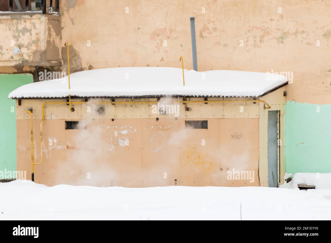 A round, metal exhaust pipe with smoke sticks out in the wall of the