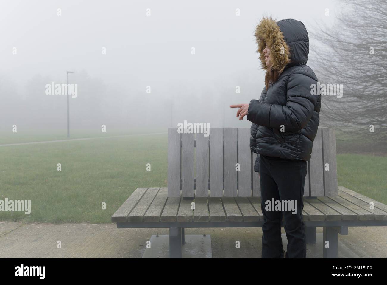 See someone in the fog outside. The girl saw a friend in the fog on a walk. Stock Photo