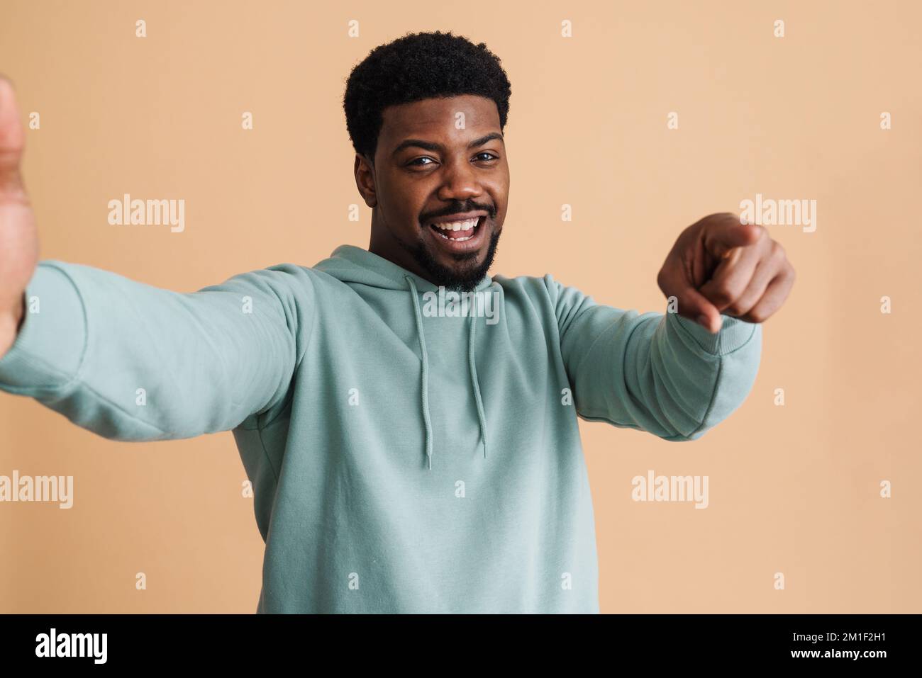 Black bearded young man smiling and taking selfie photo isolated over beige background Stock Photo