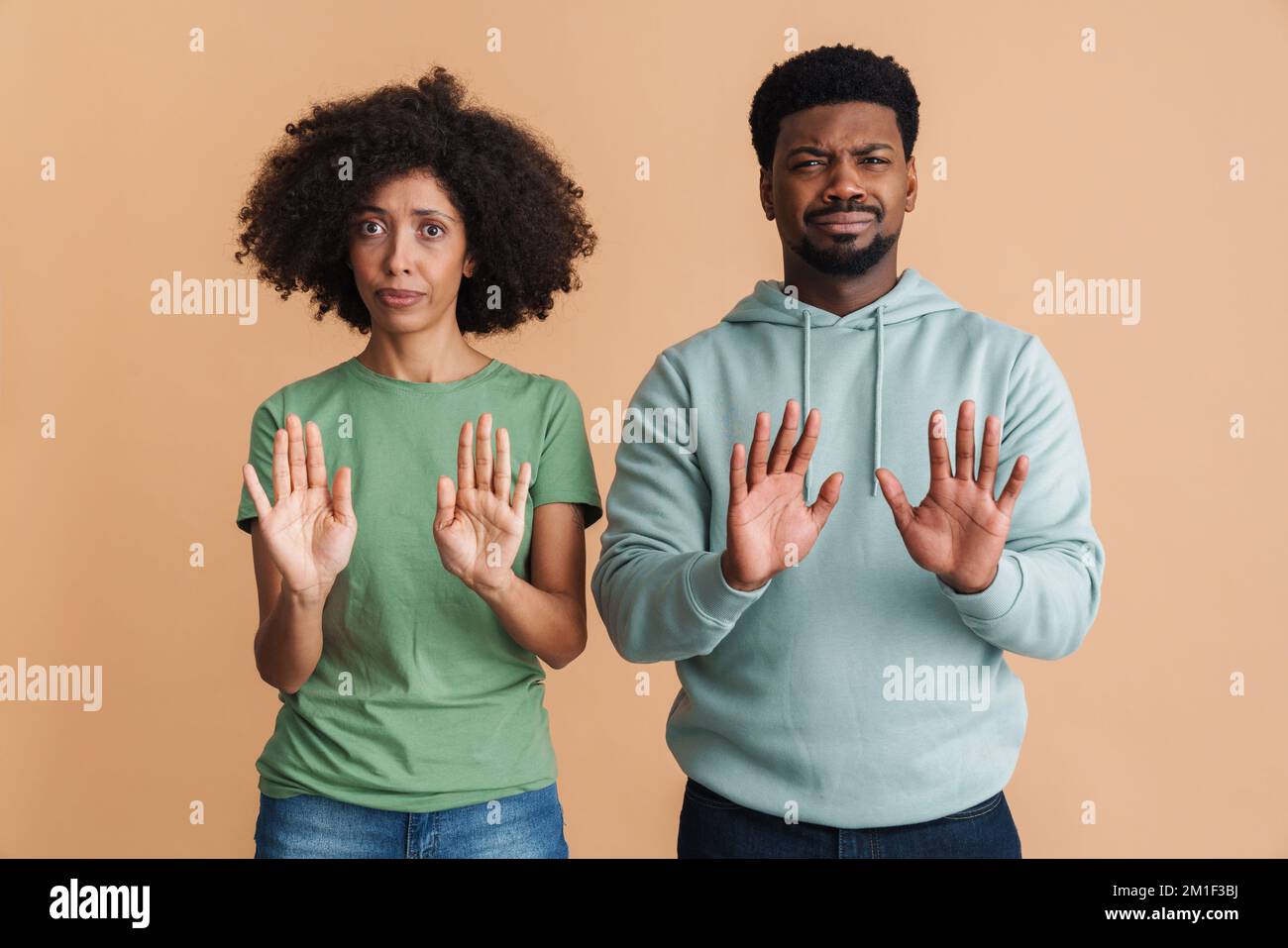 Black man and woman expressing dissatisfaction and doing stop gesture at camera isolated over beige background Stock Photo