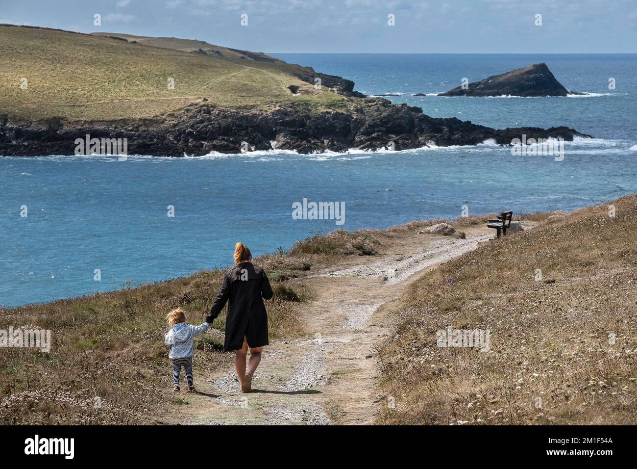 A mother and a toddler walking along the coast path on Pentire Point East in Newquay in Cornwall in the UK. Stock Photo