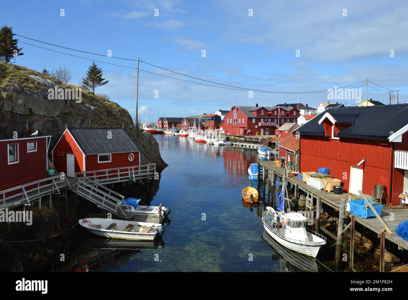 Boats and red boat houses at fishing village in small bay Stock Photo