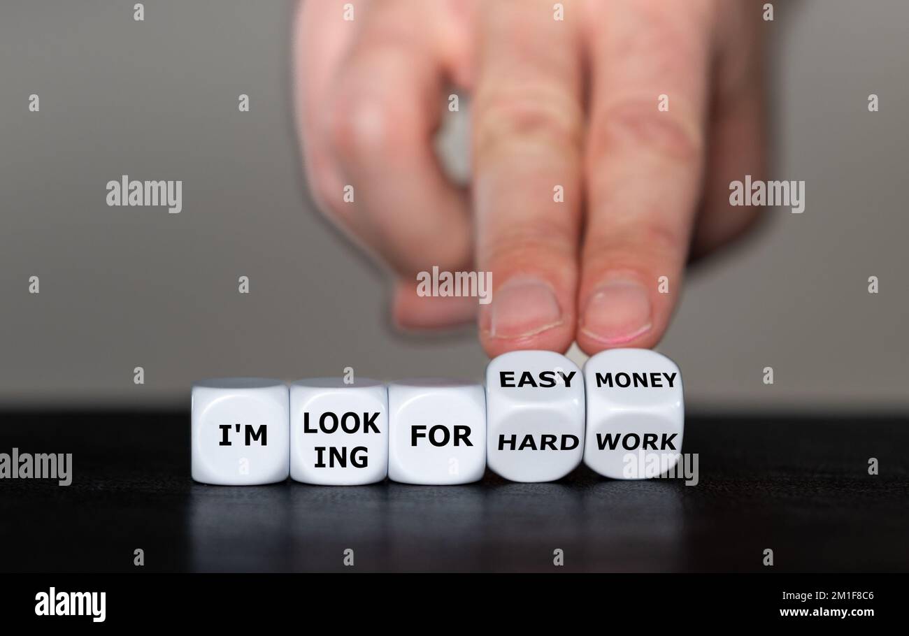 Hand turns dice and changes the expression 'I am looking for hard work' to 'I am looking for easy money'. Stock Photo