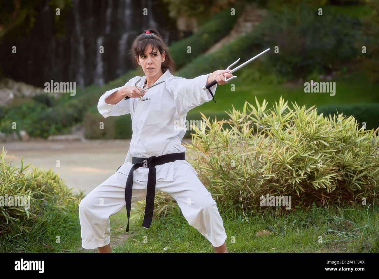 Young karate woman in fighting stance holding a pair of sai outdoors. High quality photo Stock Photo