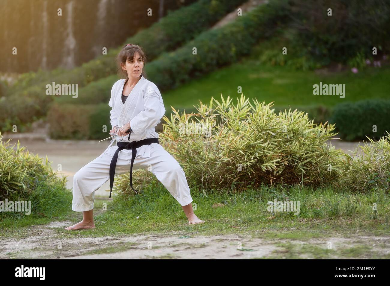 Young karate woman in fighting stance holding a pair of sai outdoors. High quality photo Stock Photo