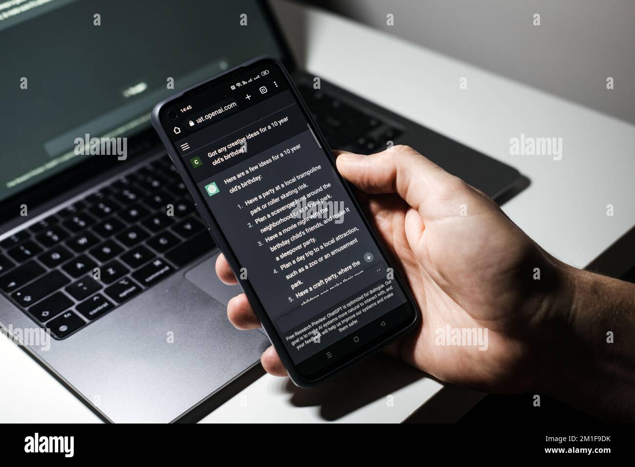 Screen with ChatGPT chat with AI or artificial intelligence. Man search for information using artificial intelligence chatbot developed by OpenAI Stock Photo