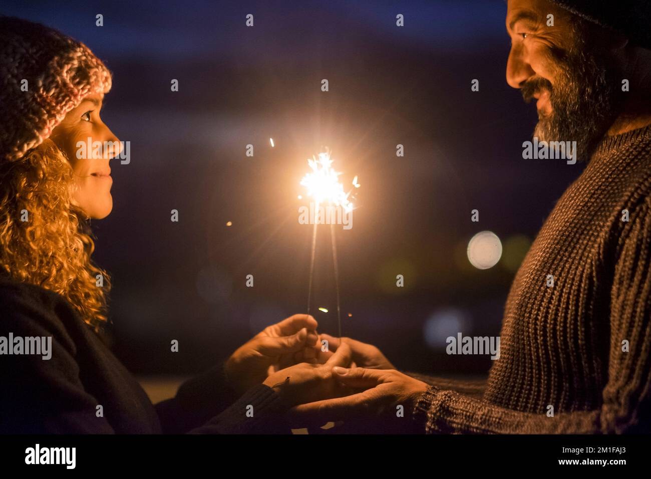 Happy couple celebrate together with love and romance in the new year eve night firing sparklers. Man and woman enjoy magic moment relationship. Matur Stock Photo