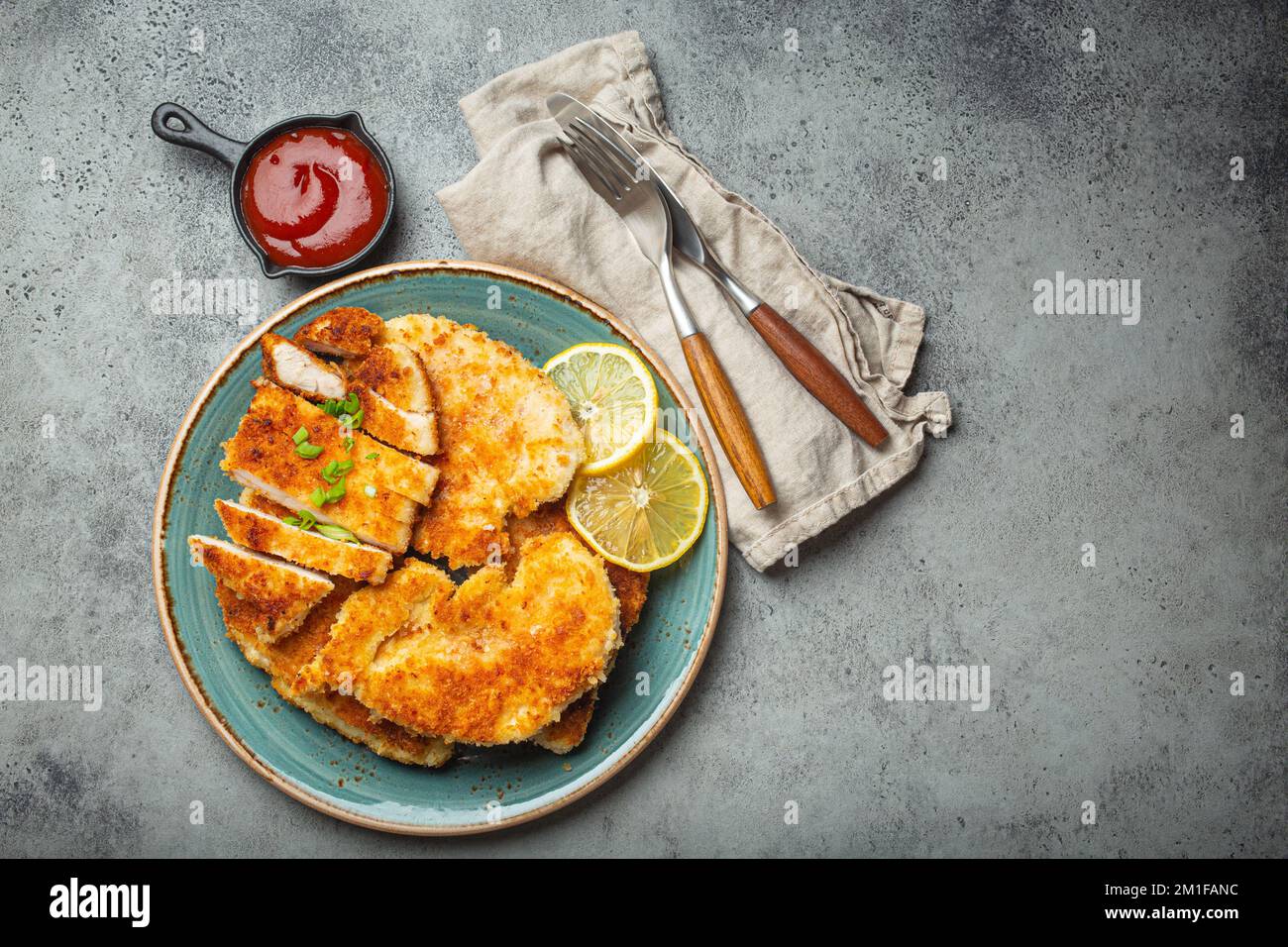 Crispy panko breaded fried chicken fillet with green salad and lemon