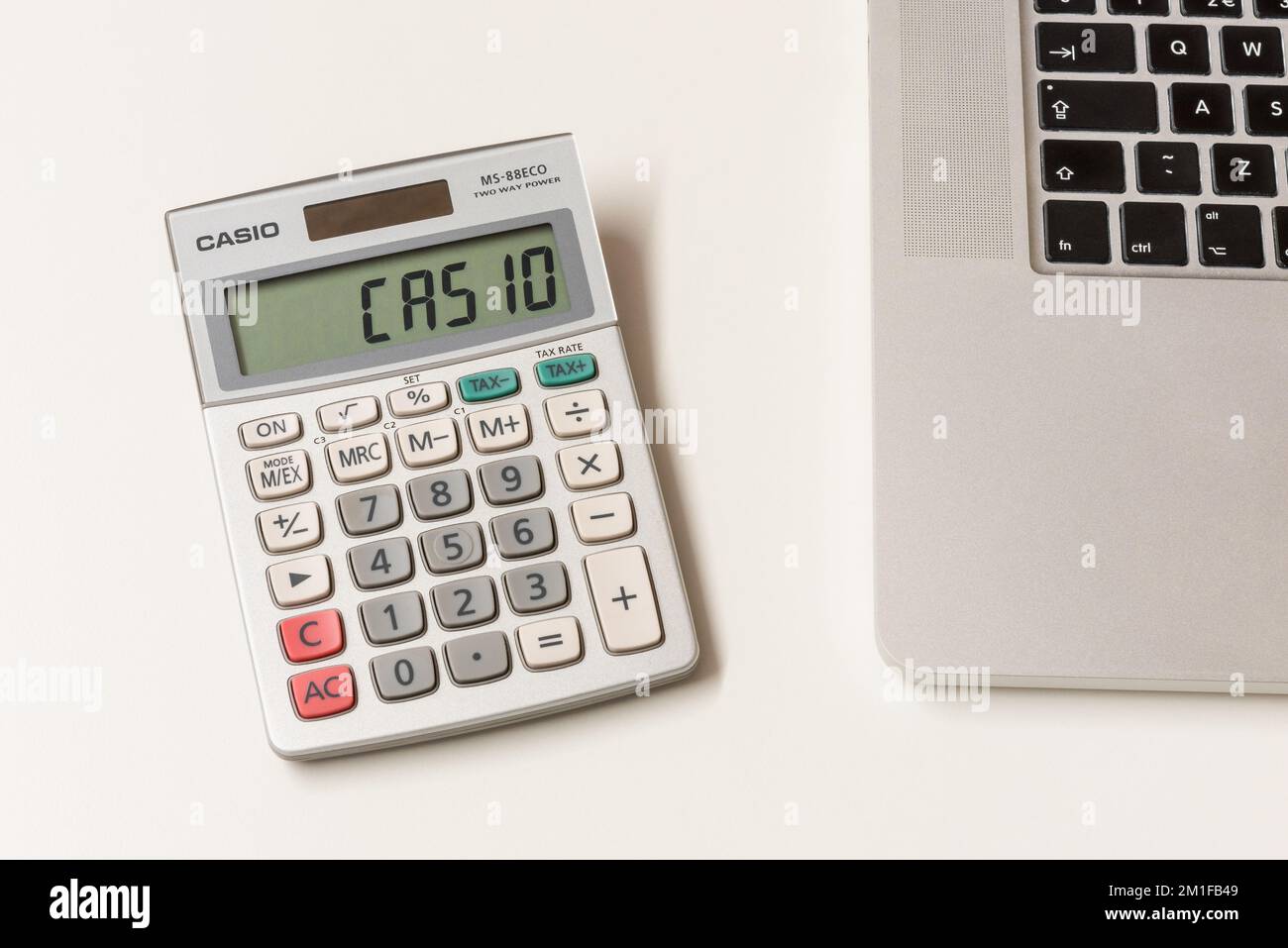 Casio Calculator on desktop, next to laptop computer. Casio is a Japanese multinational electronics manufacturing corporation, founded in 1946. Stock Photo
