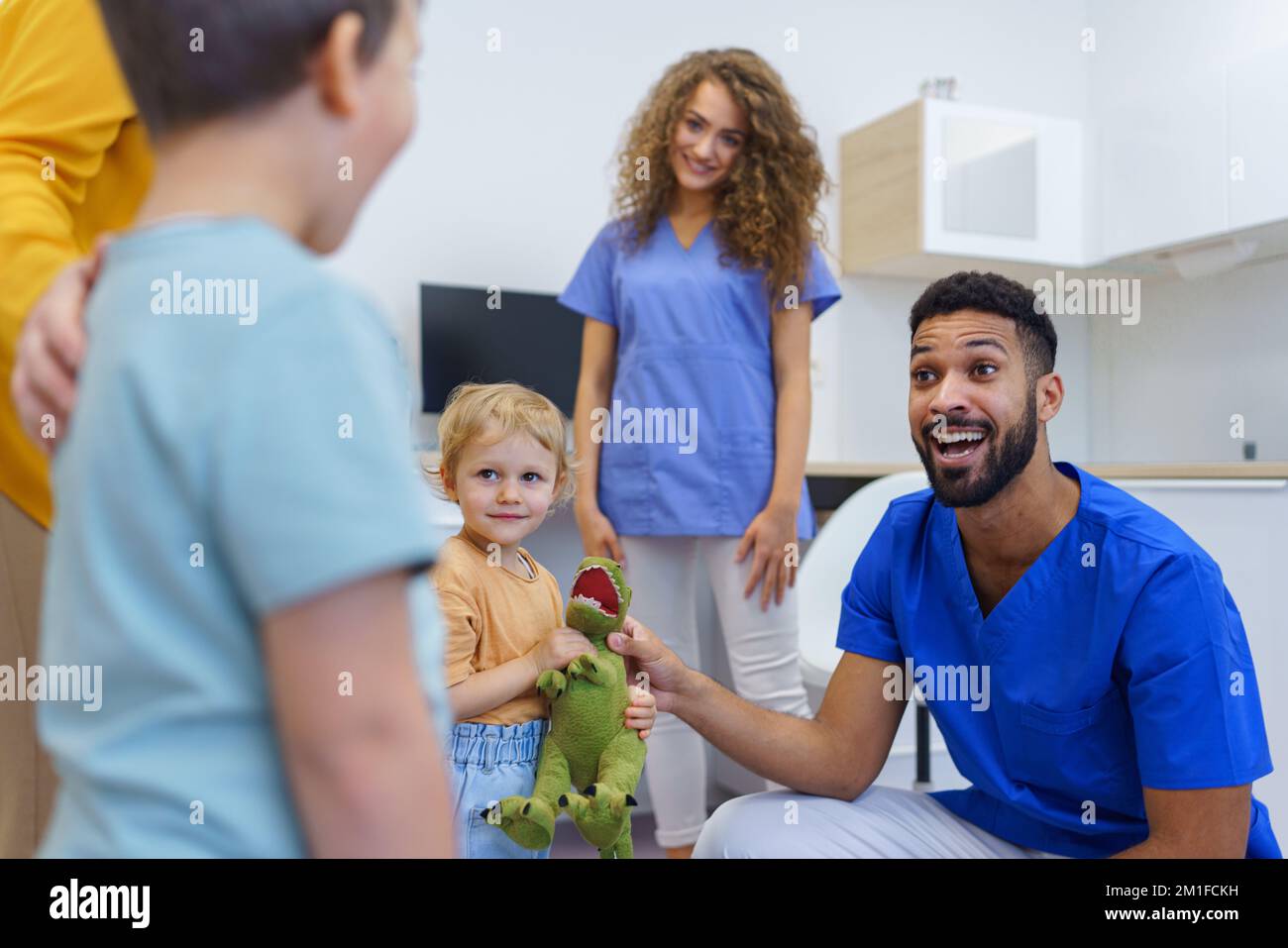 Young multiracial dentist playing with kids at his office. Stock Photo