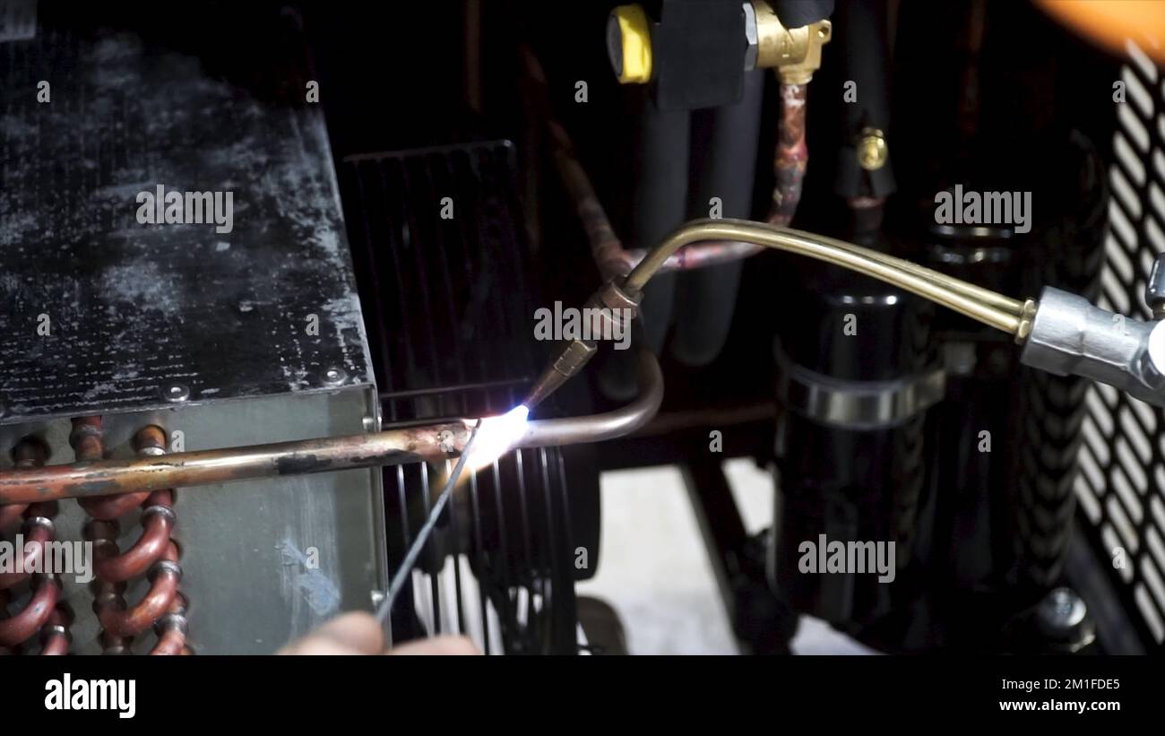 A worker is using the gas burner and the solder for soldering copper pipes. Worker burner heats