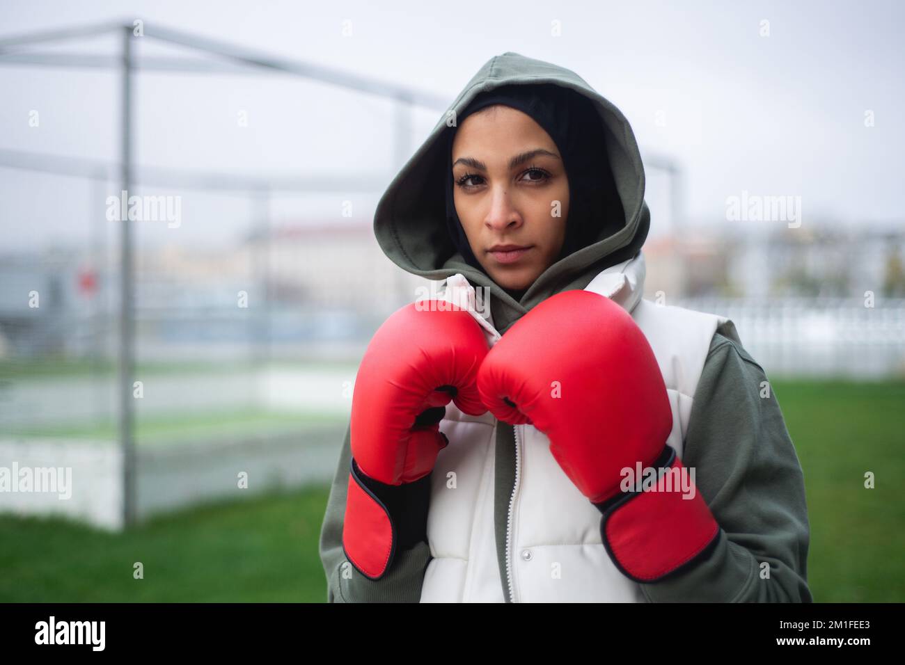 Portrait of young muslim woman with boxing gloves standing outdoor. Stock Photo