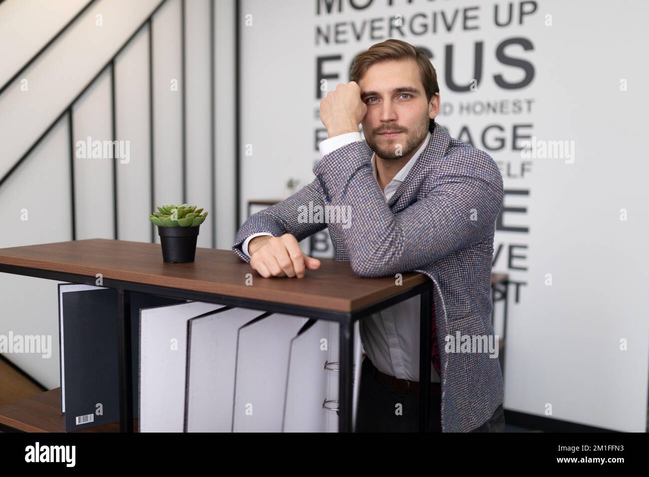 thoughtful businessman stands leaning on a shelf with folders for documents in the office Stock Photo