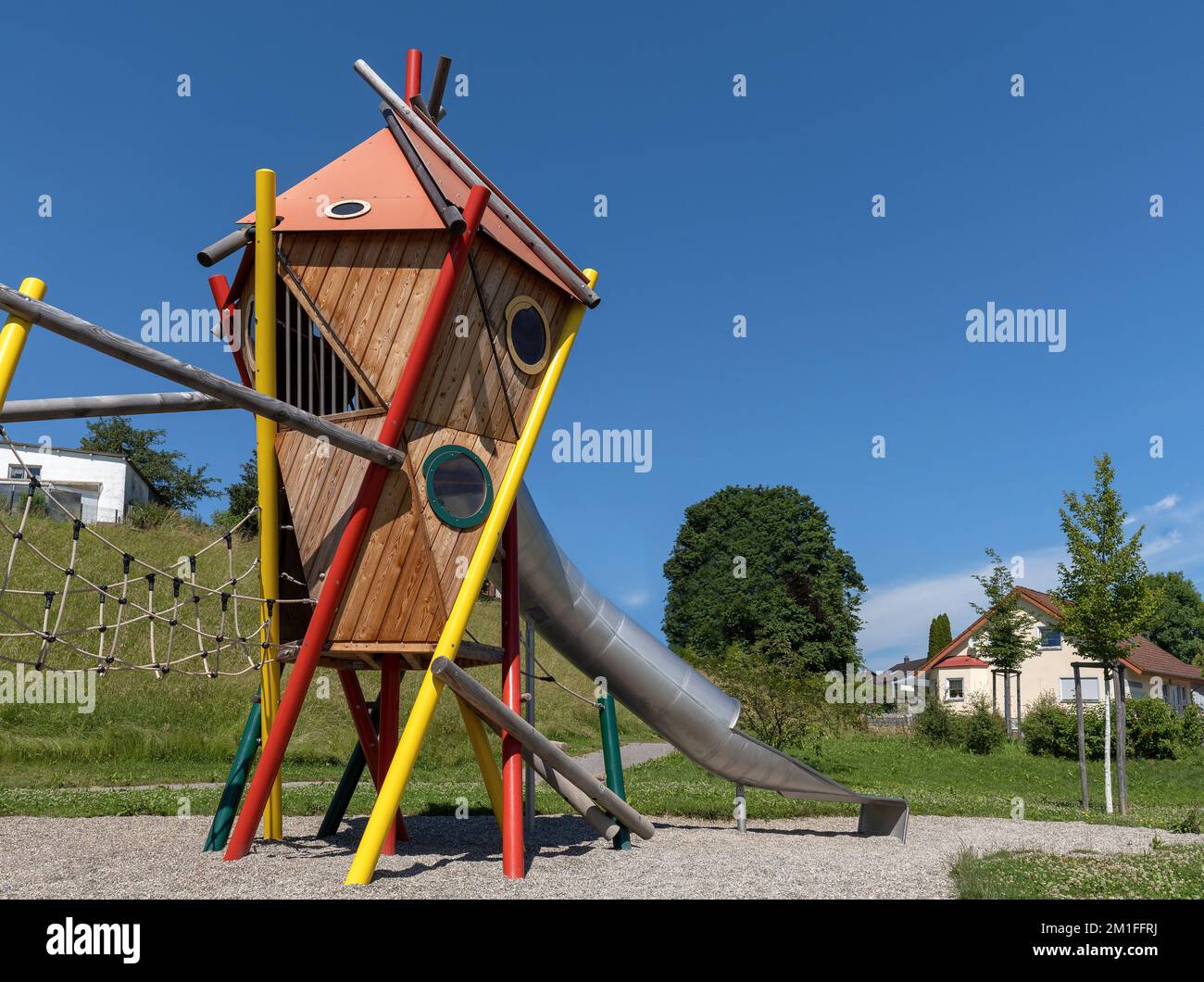 Modern colorful play tower with tunnel slide on a public playground Stock Photo