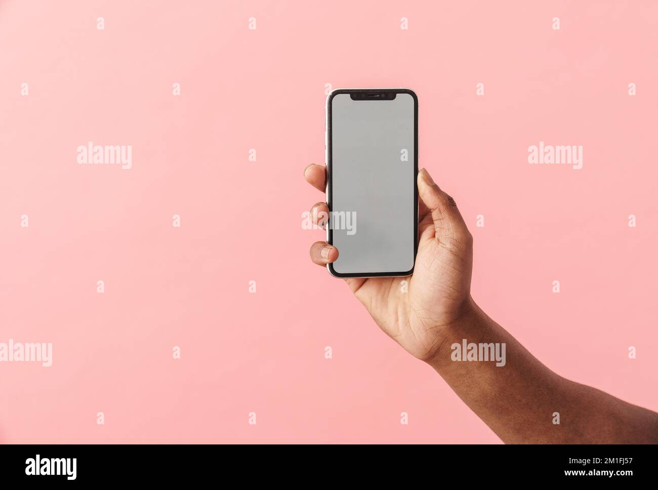 Photo of black man's hand with mobile phone isolated over pink background Stock Photo