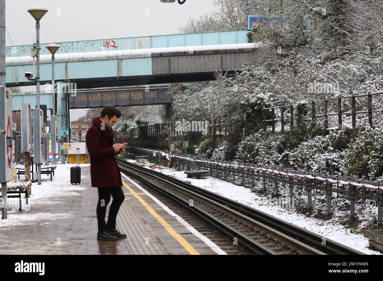 A commuter waits at the platform for a delayed train at North Acton Underground Station, west London. Snow and ice have swept across parts of the UK, with cold wintry conditions set to continue for days.. Picture date: Monday December 12, 2022. Credit: Isabel Infantes/Alamy Live News Stock Photo