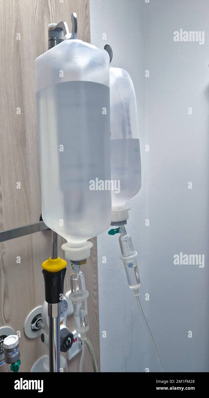 IV bottles hang on an IV stand in the hospital room Stock Photo