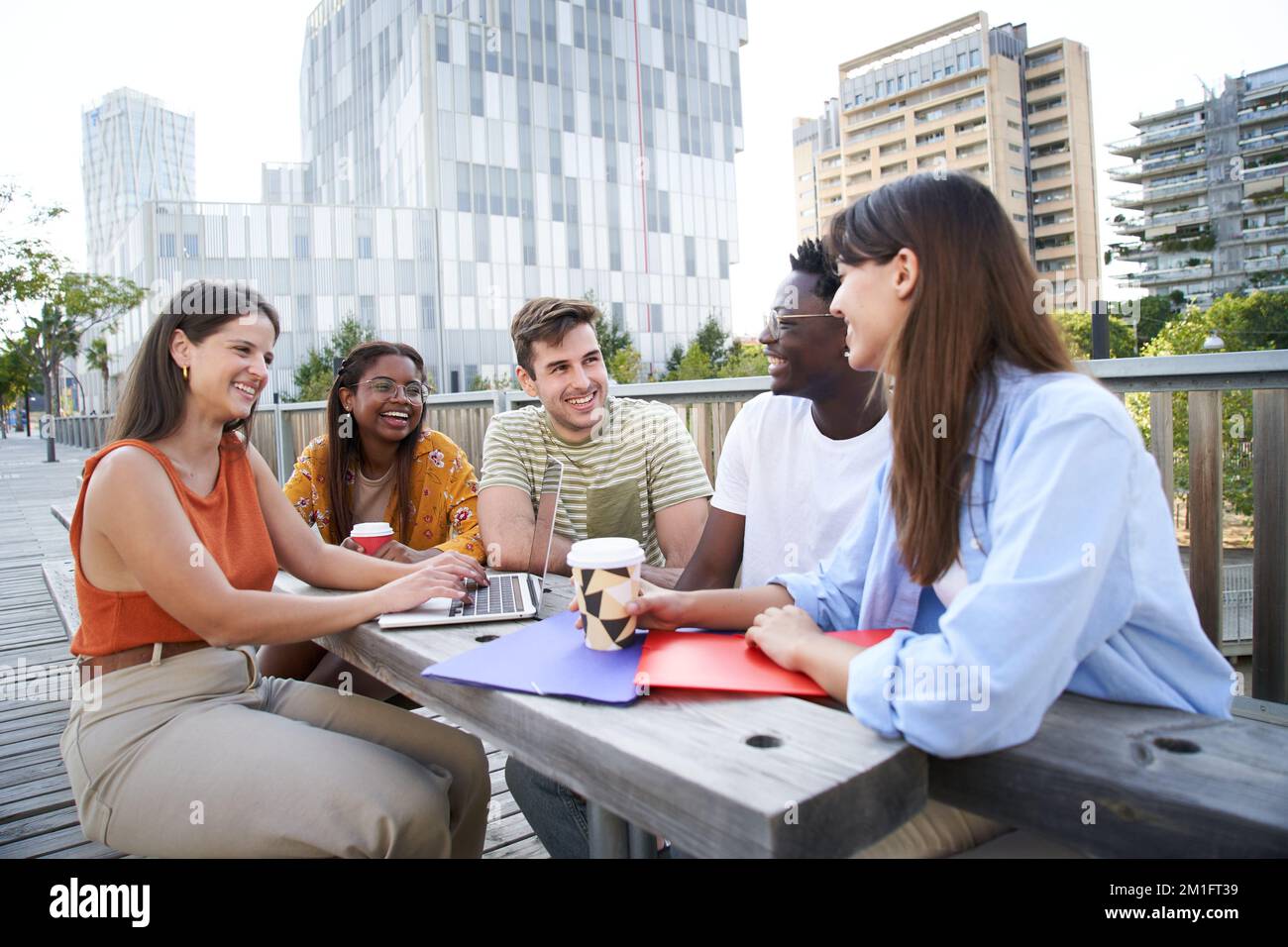 Group of cheerful students studying together outdoors. College