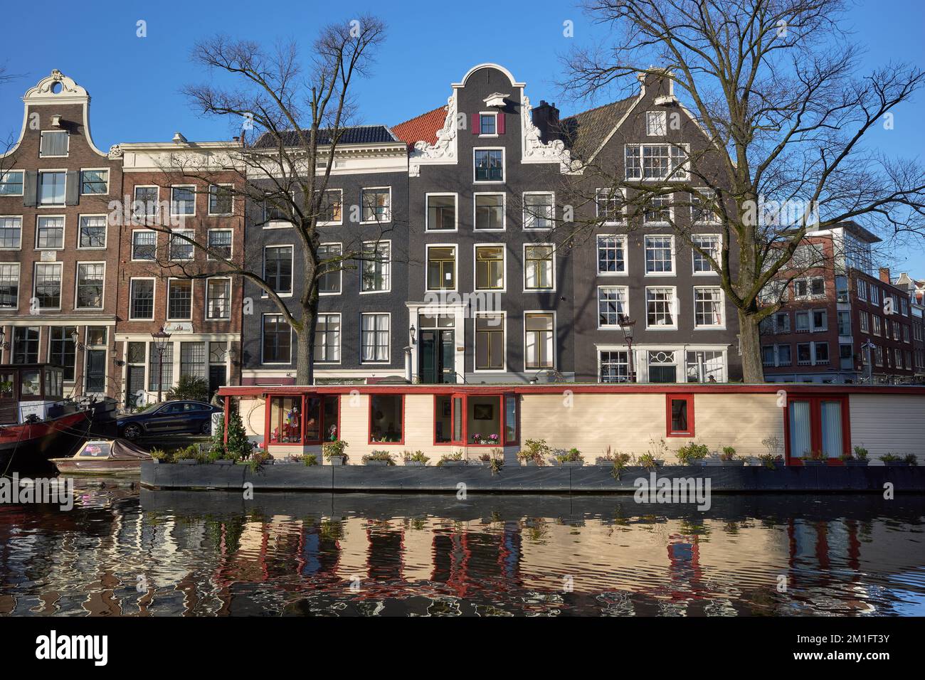 A view looking East over the Prinsengracht canal showing a houseboat moored in front of a row of traditional Amsterdam houses. Stock Photo