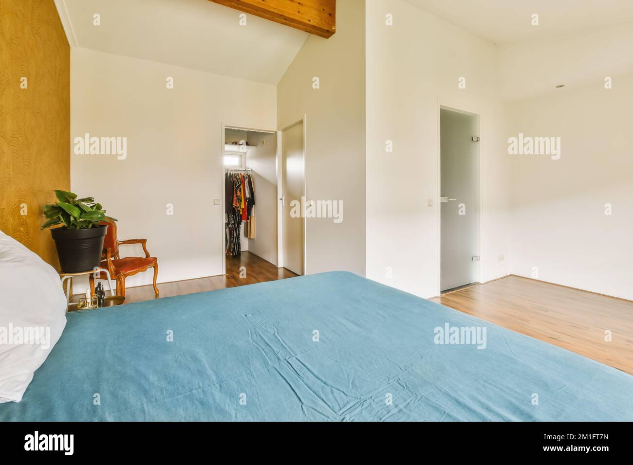 a bedroom with wood floors and white walls, including a blue bed spread
