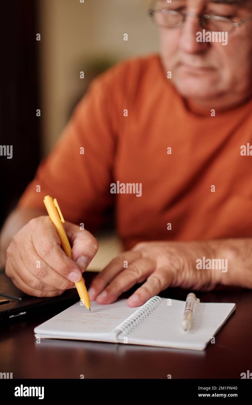 Senior man writing e-mail password in notepad to remember Stock Photo