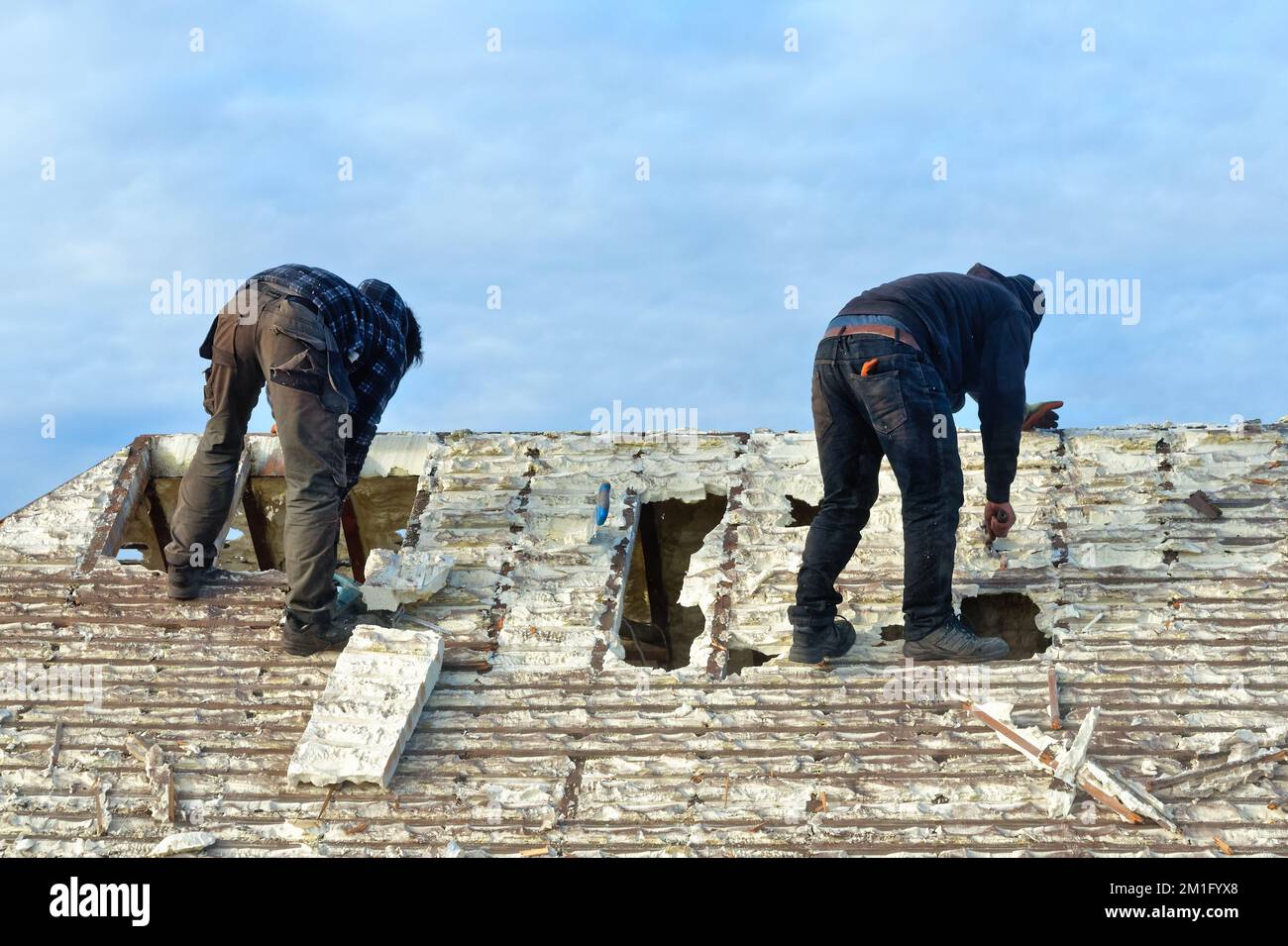 Builders removing hardened spray foam insulation from the roof space of