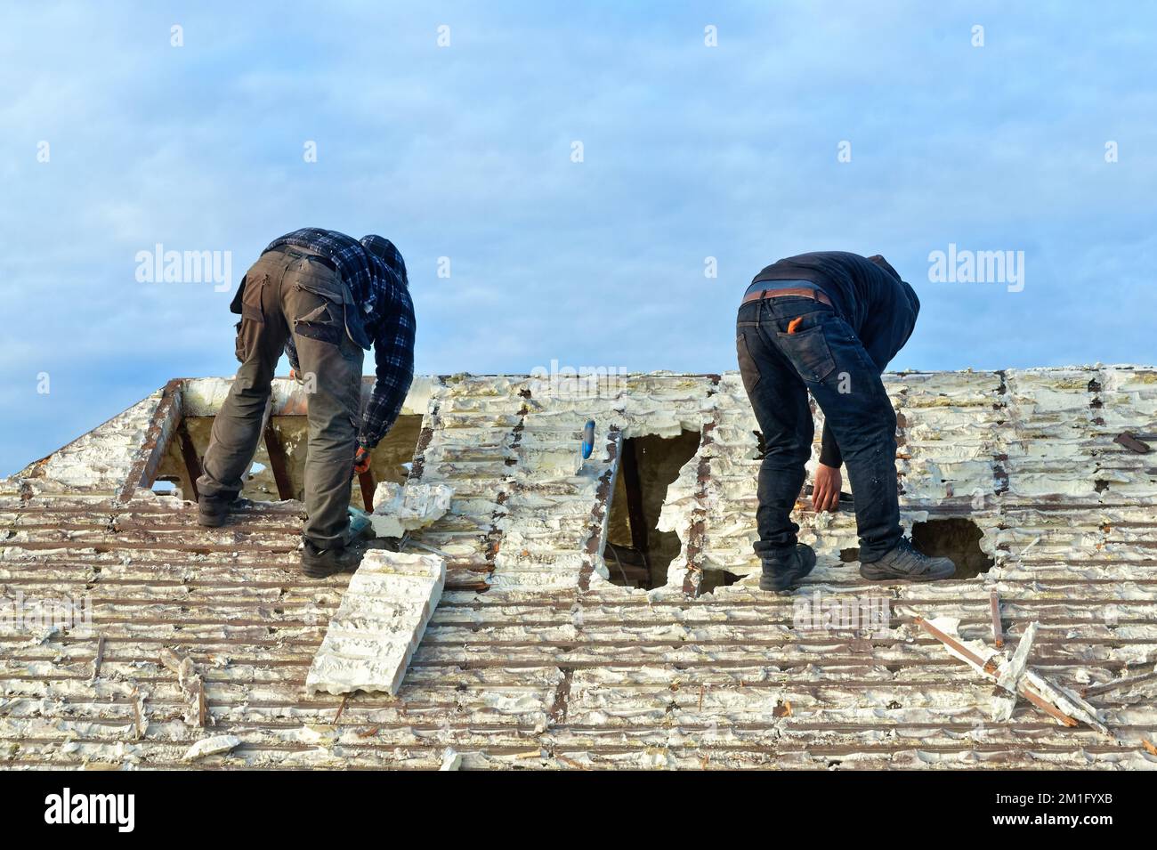 Builders removing hardened spray foam insulation from the roof space of