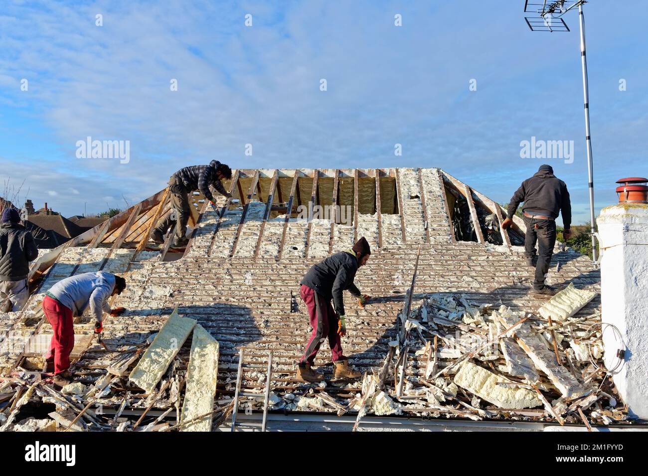 Builders removing hardened spray foam insulation from the roof space of