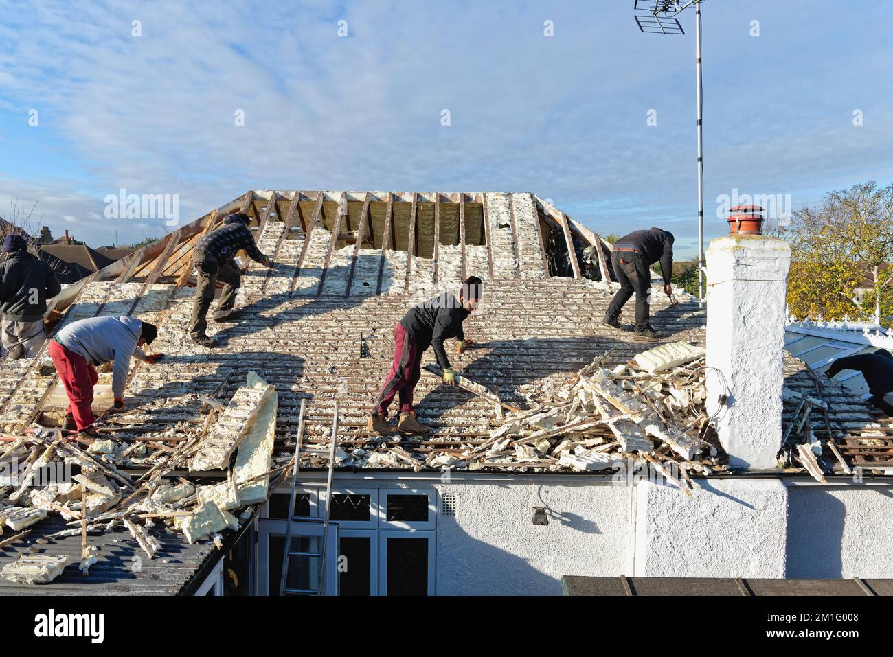 Builders removing hardened spray foam insulation from the roof space of