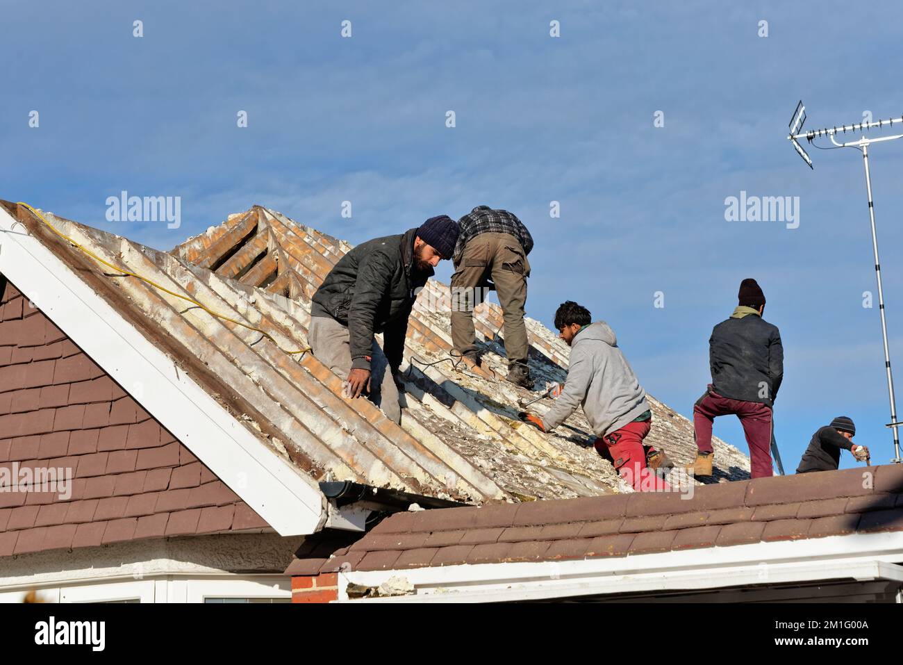 Builders removing hardened spray foam insulation from the roof space of