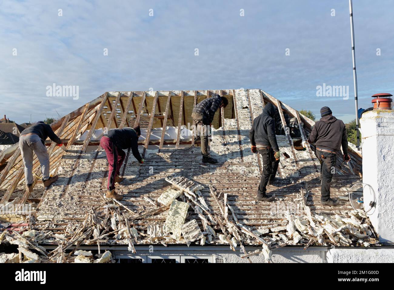 Builders removing hardened spray foam insulation from the roof space of