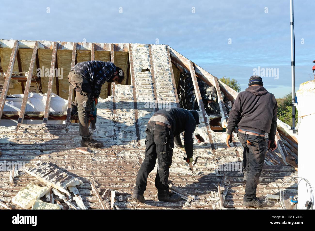 Builders removing hardened spray foam insulation from the roof space of