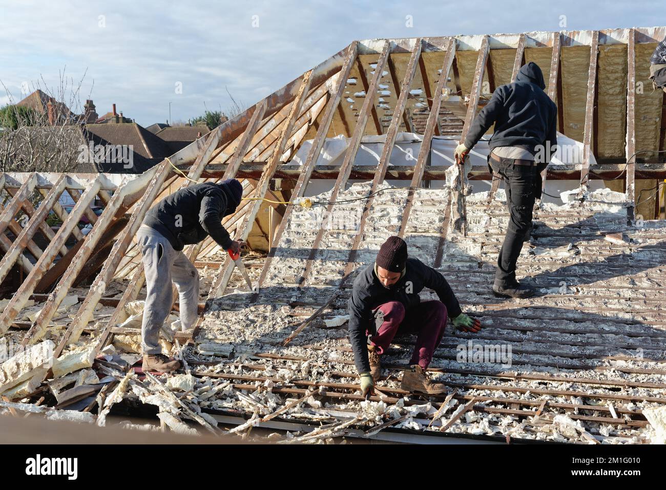 Builders removing hardened spray foam insulation from the roof space of