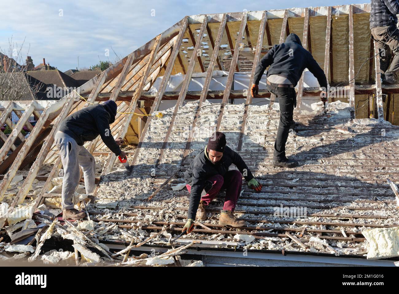 Builders removing hardened spray foam insulation from the roof space of