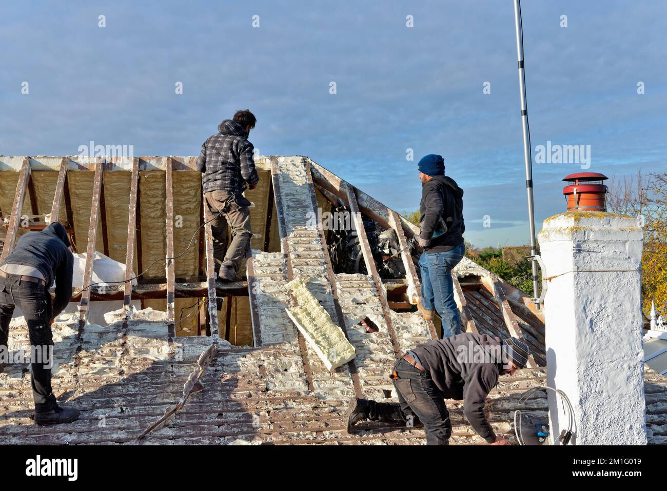 Builders removing hardened spray foam insulation from the roof space of