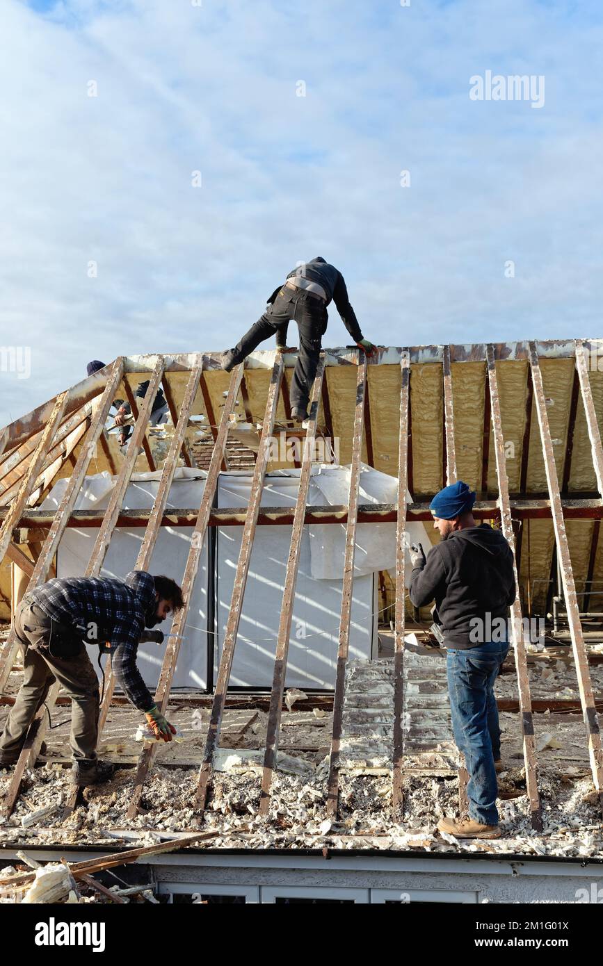 Builders removing hardened spray foam insulation from the roof space of