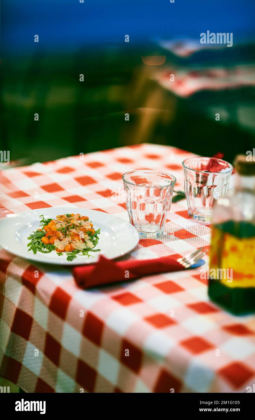 Gnocchi with tomato sauce and rocket salad with parmesan cheese on a table of a typical Italian Trattoria. Stock Photo