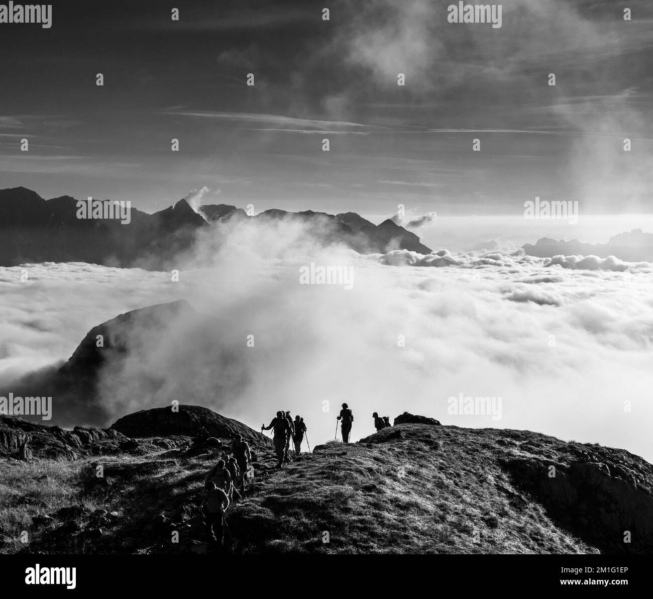 Hikers ascend the mountain, breaking out of the clouds. Tide of clouds. Hochkönig mountain. Berchtesgaden Alps, Salzburgerland, Austria. Stock Photo