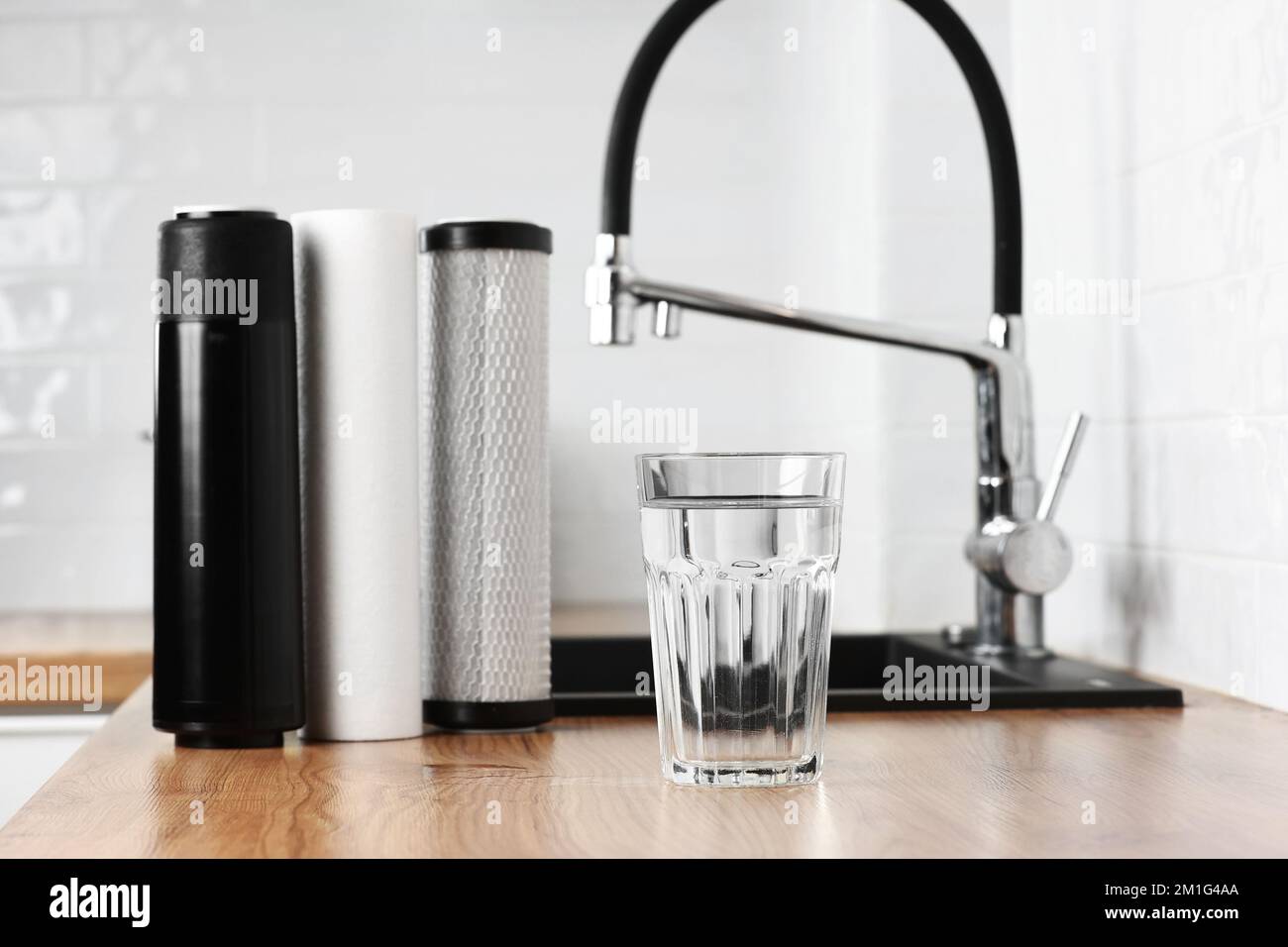 A glass of clean fresh water and set of filter cartridges on wooden ...